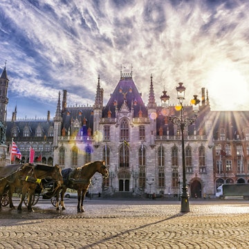 Horse carriages on Grote Markt square in medieval city Brugge at morning on background sunrise, Belgium. Shallow depth of field; Shutterstock ID 469563257; Your name (First / Last): redownload; GL account no.: redownload; Netsuite department name: redownload; Full Product or Project name including edition: redownload