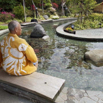 Elderly couple in kimonos dipping feet in ornamental foot bath, Oedo Onsen Monotogari, Odaiba.