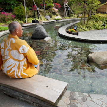 Elderly couple in kimonos dipping feet in ornamental foot bath, Oedo Onsen Monotogari, Odaiba.