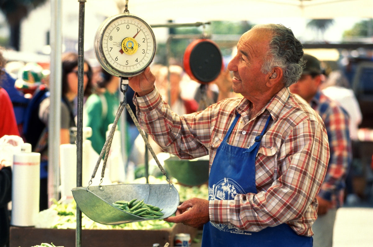 Farmer weighing produce at outdoor market,Santa Monica,California,USA