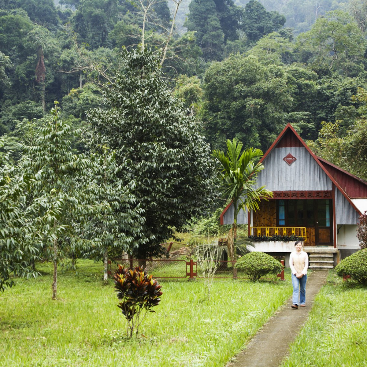 Woman walking in front of A-frame hut accomodation.