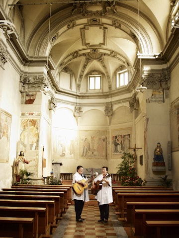 Two women singing and playing guitar in Bedigliora’s church.