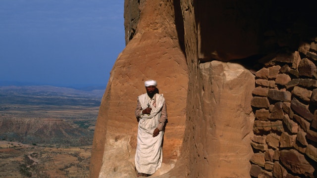 Priest on a cliff ledge in front of Abuna Yemata Guh church in Gheralta.