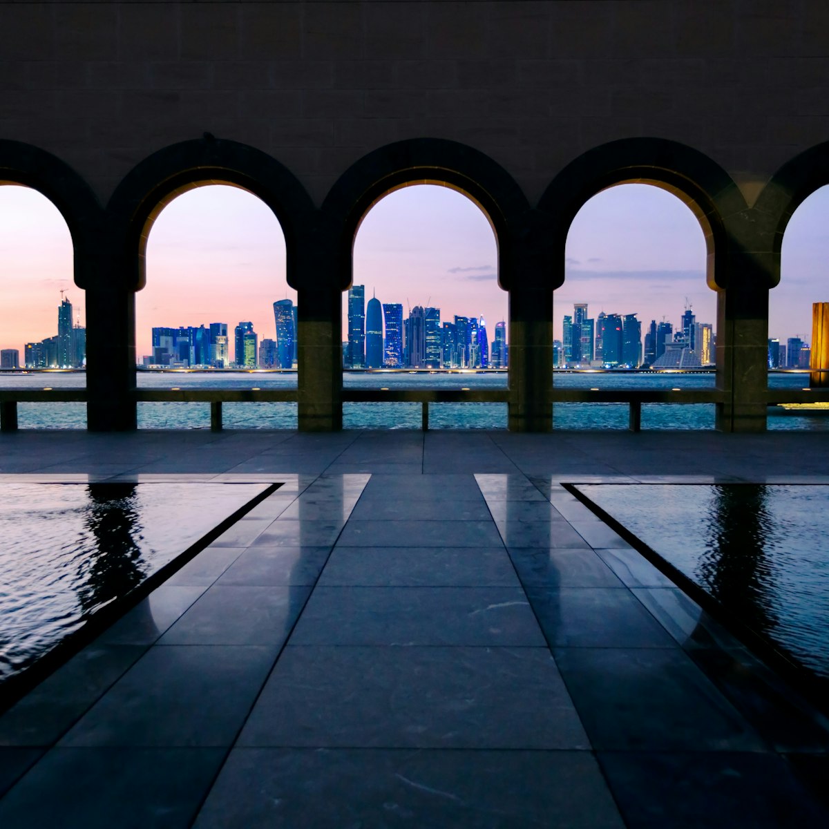 Qatar, Doha. Cityscape at night from promenade near the Corniche on Doha harbor