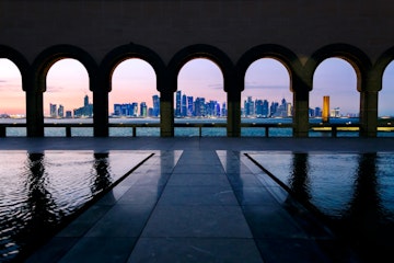Qatar, Doha. Cityscape at night from promenade near the Corniche on Doha harbor