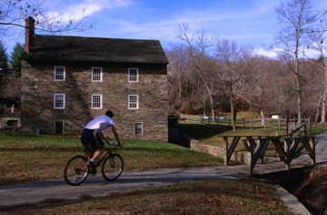Man cycling past building in Rock Creek Park.