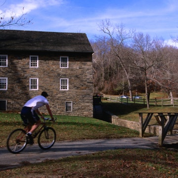 Man cycling past building in Rock Creek Park.