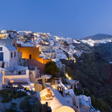 Rooftops of houses and villas on rim of caldera at dusk.