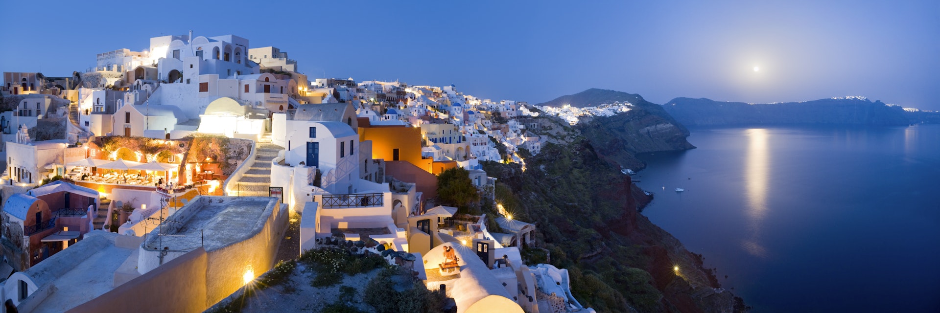 Rooftops of houses and villas on rim of caldera at dusk.