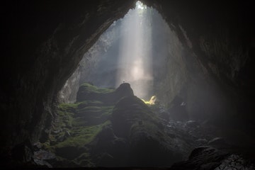 A caver stands under a beam of sunlight passing through a doline, into the world's biggest cave, Hang Son Doong. i was lucky enough to join a 6 day expedition into the cave in April this year.