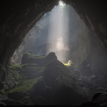 A caver stands under a beam of sunlight passing through a doline, into the world's biggest cave, Hang Son Doong. i was lucky enough to join a 6 day expedition into the cave in April this year.