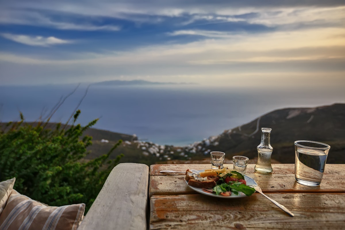 A tsipouro drink with meze and great view to the Aegean, in Tinos island, Greece