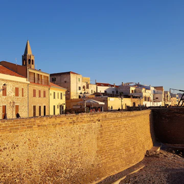 Sea wall of Alghero. North of Sardinia. Itlay.Alghero's golden sea walls, built around the centro storico by the Aragonese in the 16th century, are a highlight of the town's historic cityscape.; Shutterstock ID 576280477; Your name (First / Last): Anna Tyler; GL account no.: 65050; Netsuite department name: Online Editorial; Full Product or Project name including edition: destination-image-southern-europe