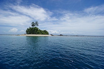 Small island on horizon with palm trees