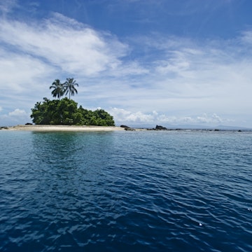 Small island on horizon with palm trees