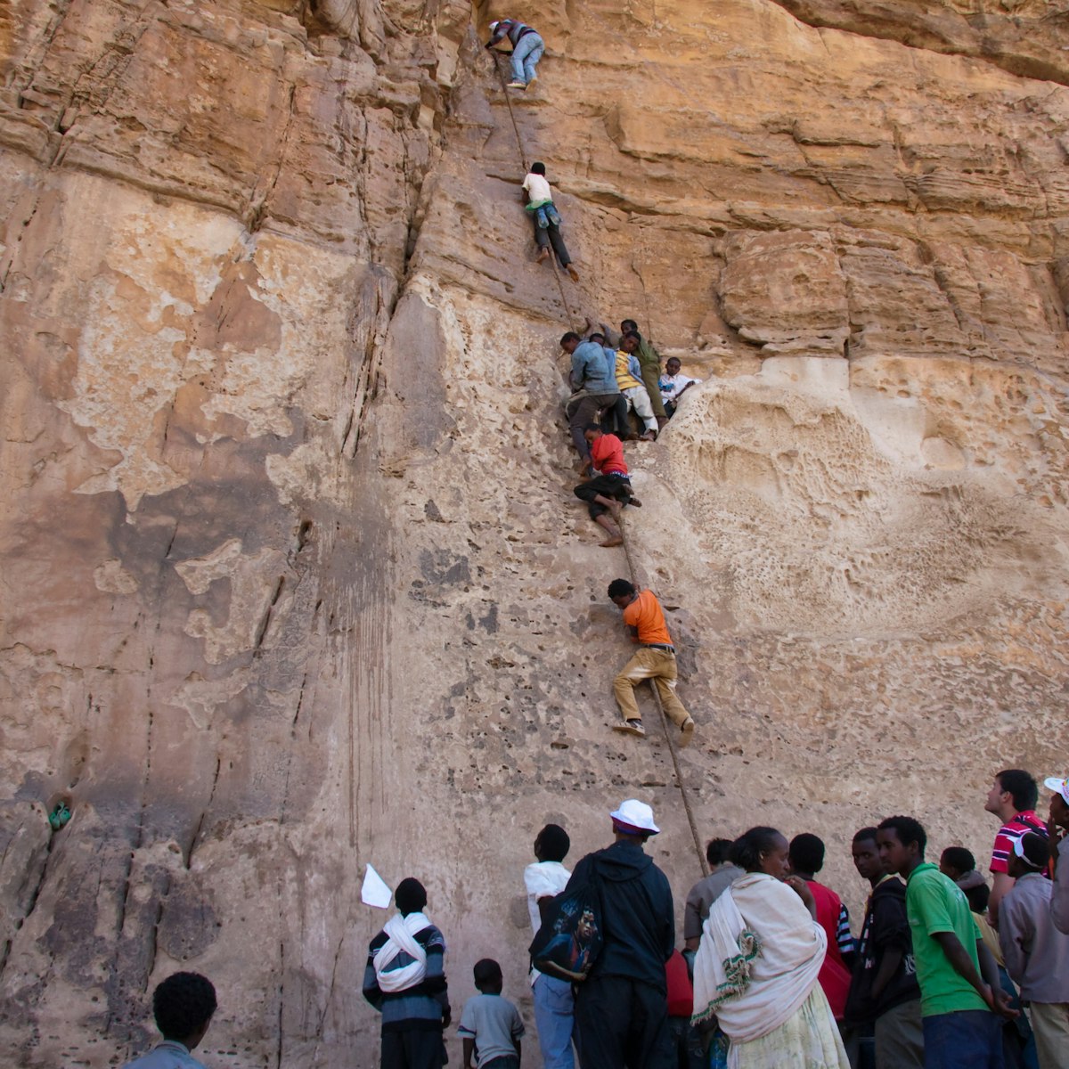 Orthodox Christian pilgrim men being hauled up a 15m cliff face by monks to reach the mountain-top church and monastery of Debre Damo, Northern Tigray province, Ethiopia.