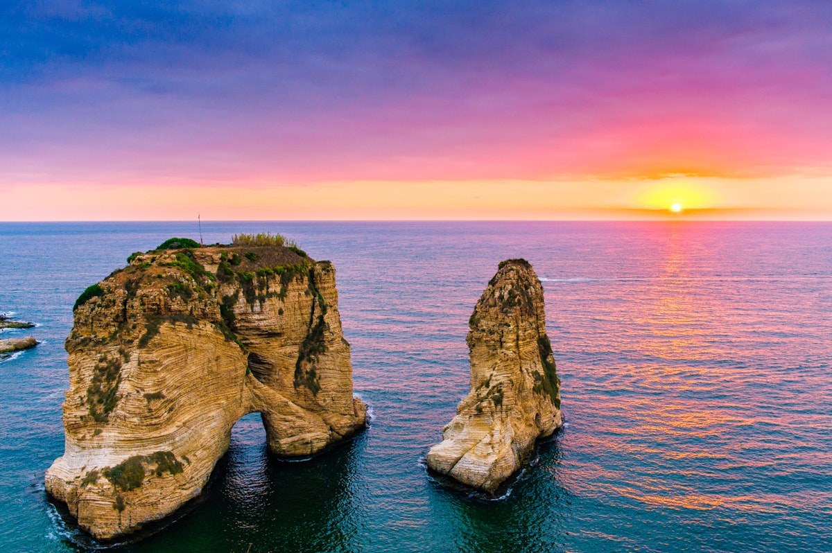 Beautiful sunset on Raouche, Pigeons' Rock. In Beirut, Lebanon.Sun and Stones are reflected in water.dense clouds in the sky.; Shutterstock ID 706503574; Your name (First / Last): Lauren Keith; GL account no.: 65050; Netsuite department name: Online Editorial; Full Product or Project name including edition: Beirut Guides app update