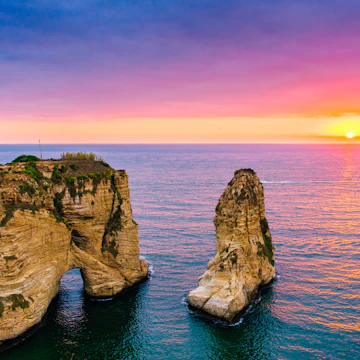 Beautiful sunset on Raouche, Pigeons' Rock. In Beirut, Lebanon.Sun and Stones are reflected in water.dense clouds in the sky.; Shutterstock ID 706503574; Your name (First / Last): Lauren Keith; GL account no.: 65050; Netsuite department name: Online Editorial; Full Product or Project name including edition: Beirut Guides app update