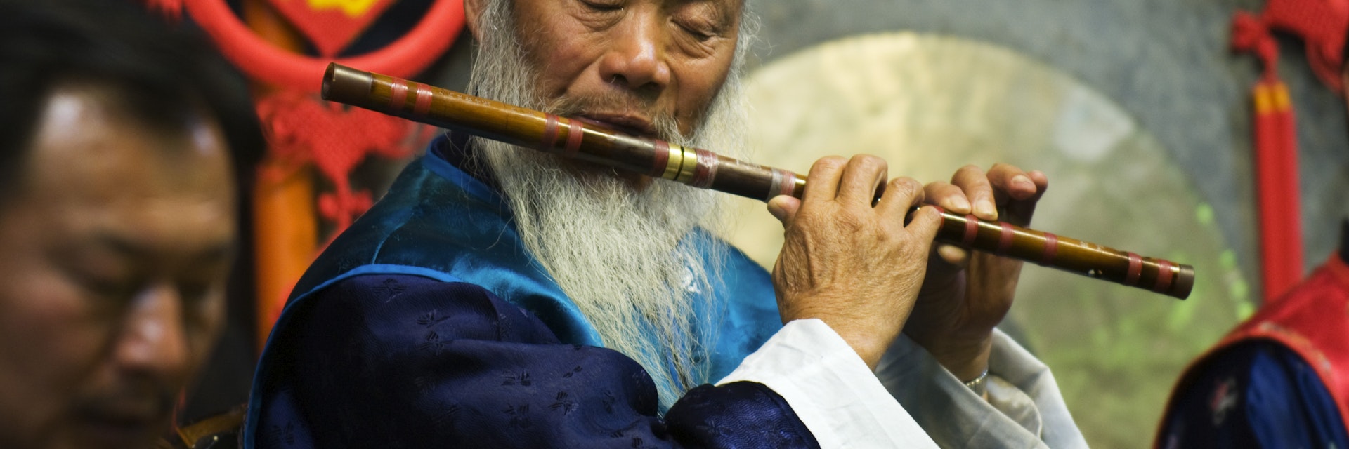 China, Yunnan province, Lijiang town. Naxi orchestra musician playng the flute at the Unesco World Heritage Site