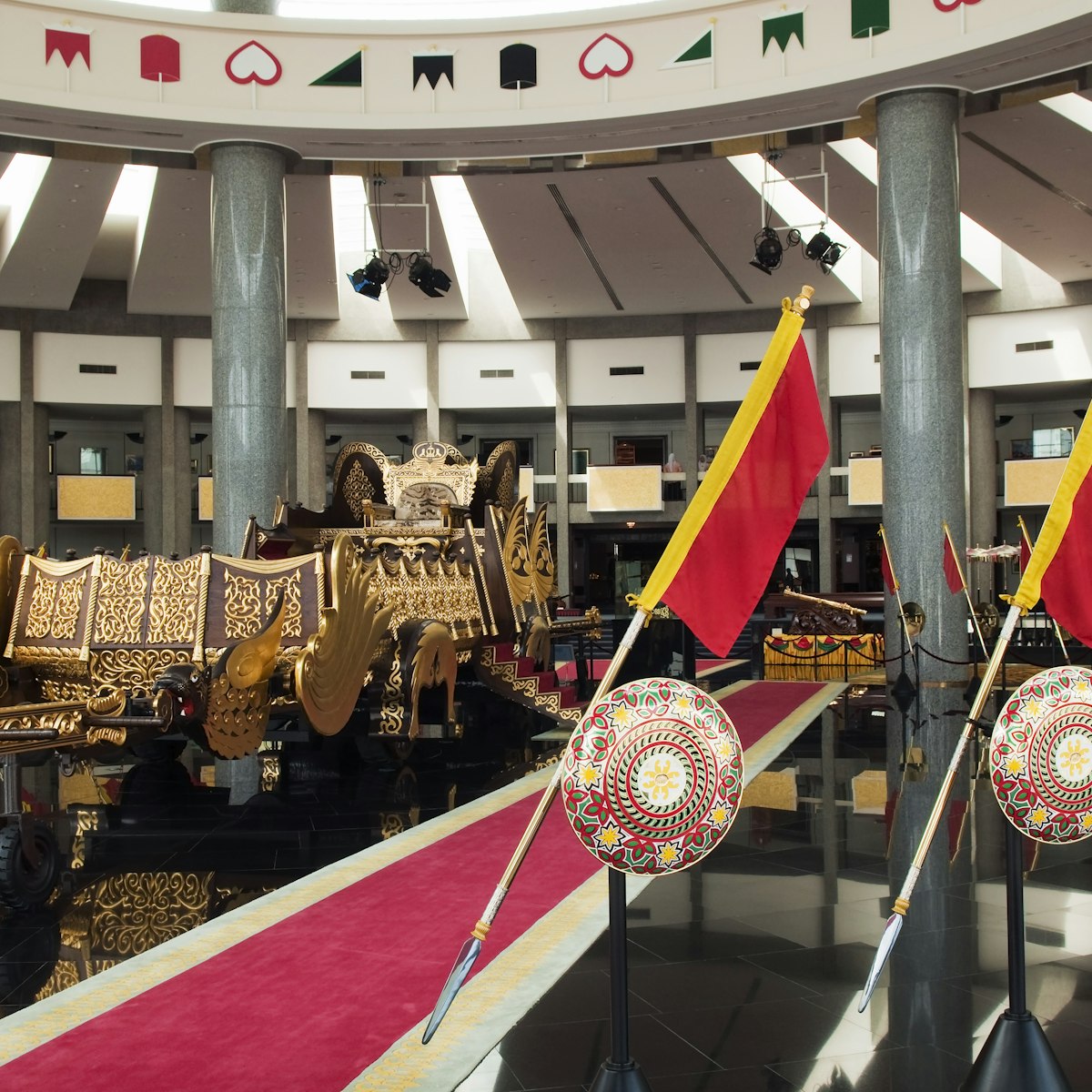 Interior of ther Royal Regalia Museum with sultan's gilded coronation cart and shields.