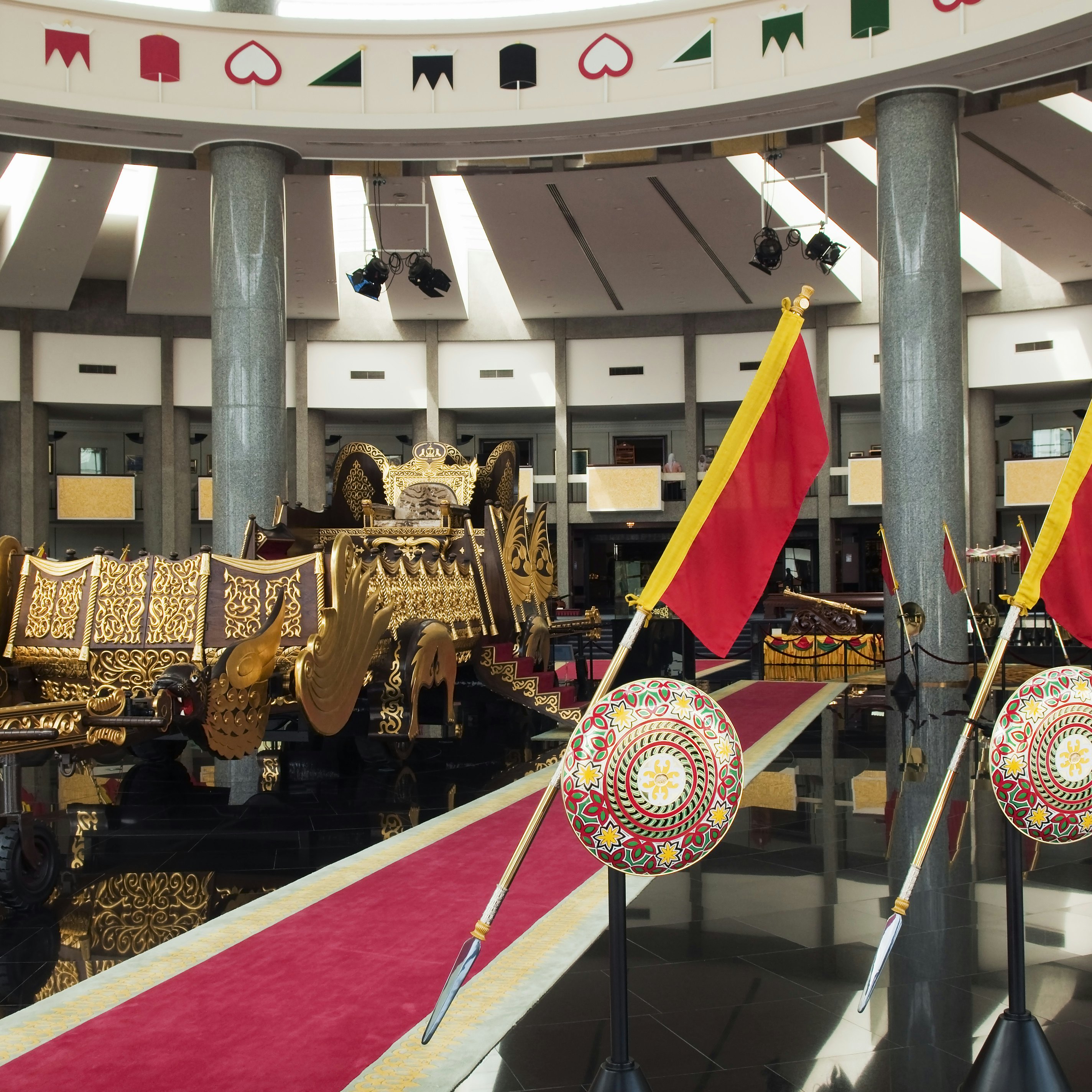Interior of ther Royal Regalia Museum with sultan's gilded coronation cart and shields.