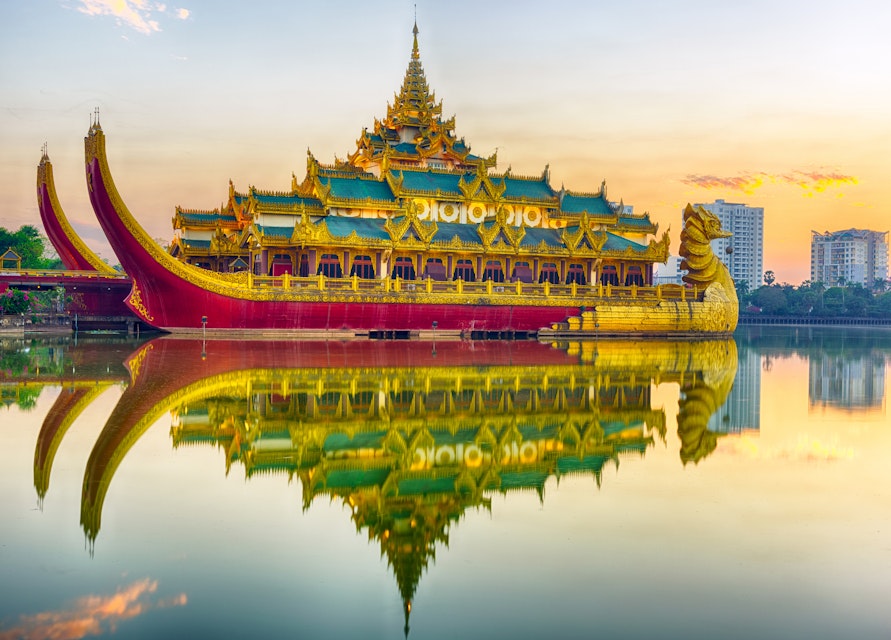 Golden Karaweik palace reflecting on Kandawgyi lake looks like an ancient royal barge. Sunset time. Yangon, Myanmar ; Shutterstock ID 420418678; Your name (First / Last): Laura Crawford; GL account no.: 65050; Netsuite department name: Online Editorial; Full Product or Project name including edition: Yangon images for city app POIs