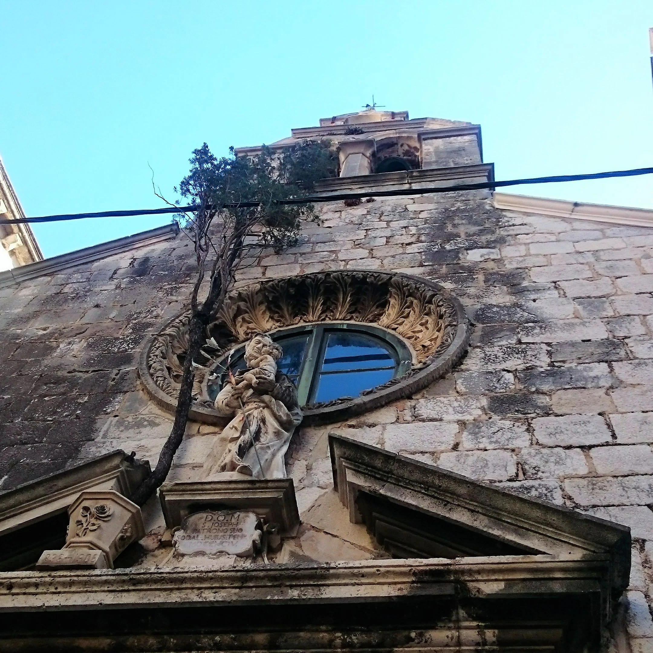 The cypress tree and Statue of St. Joseph's on the front facade
