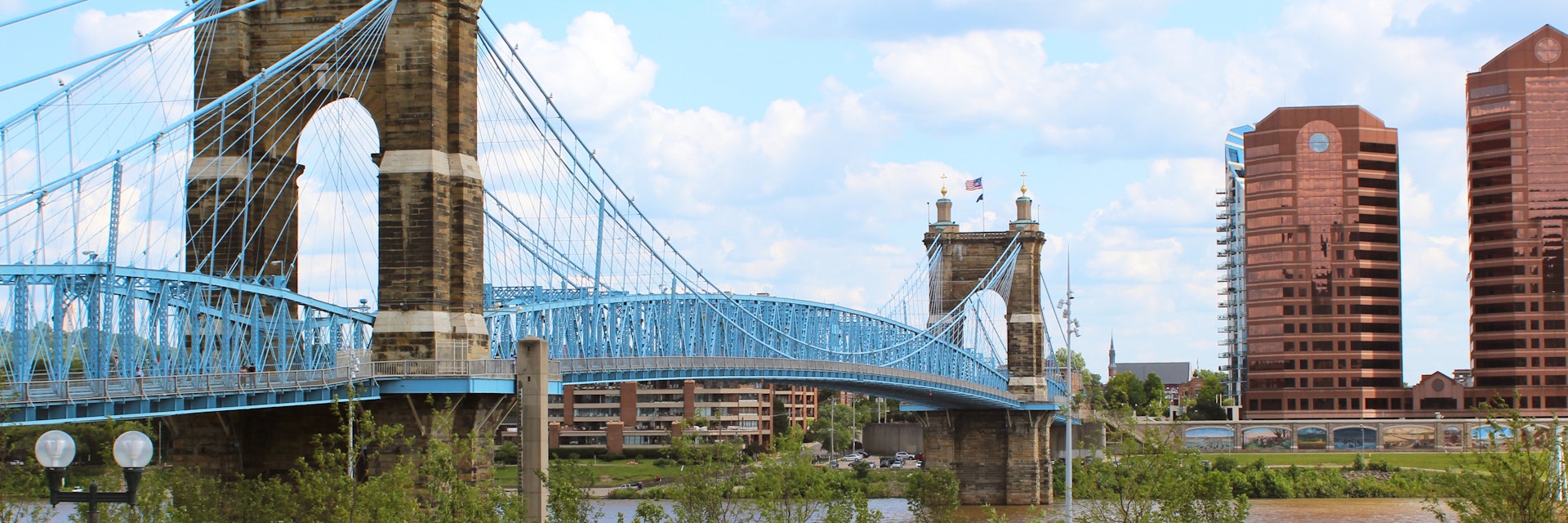 A landscape view of Cincinnati's Smale Riverfront Park and the Roebling Suspension Bridge that crosses over the Ohio River and connects Cincinnati, Ohio to Covington, Kentucky.