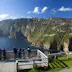 People on viewing platform beneath huge sea cliffs