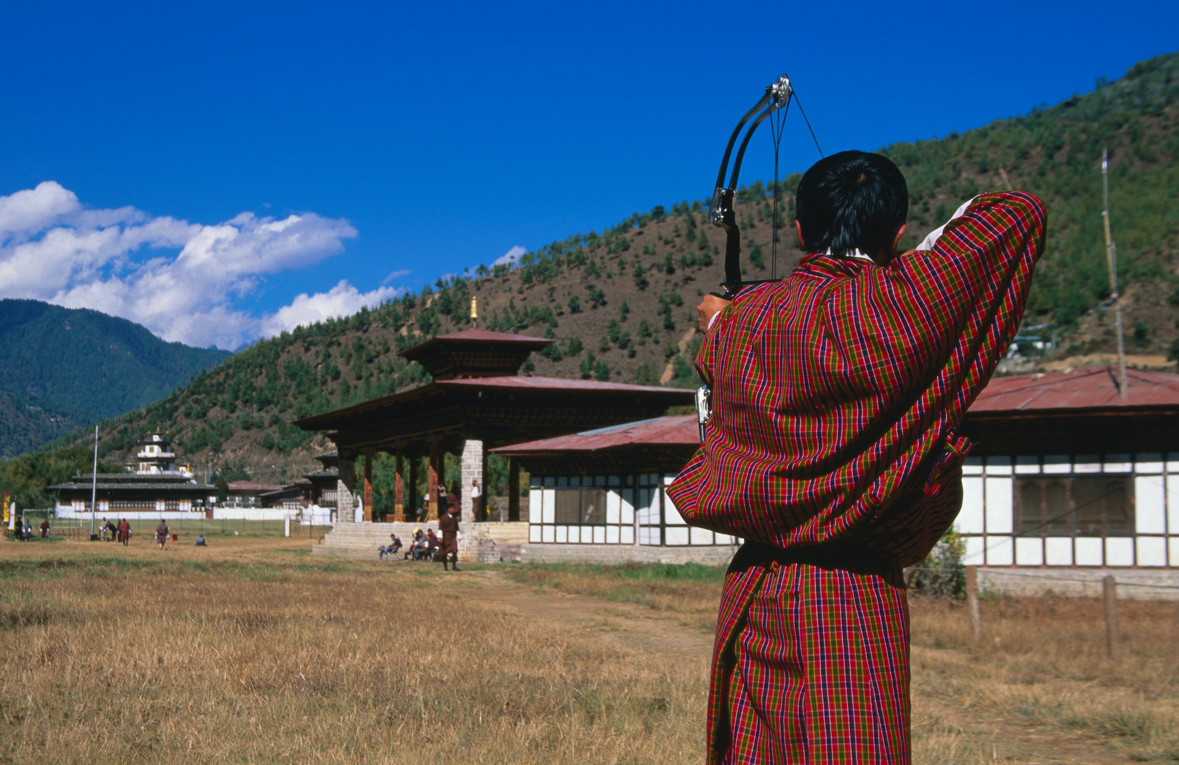 Archer in traditional dress drawing bow in archery competition at national archery ground, Changlimithang Stadium.
