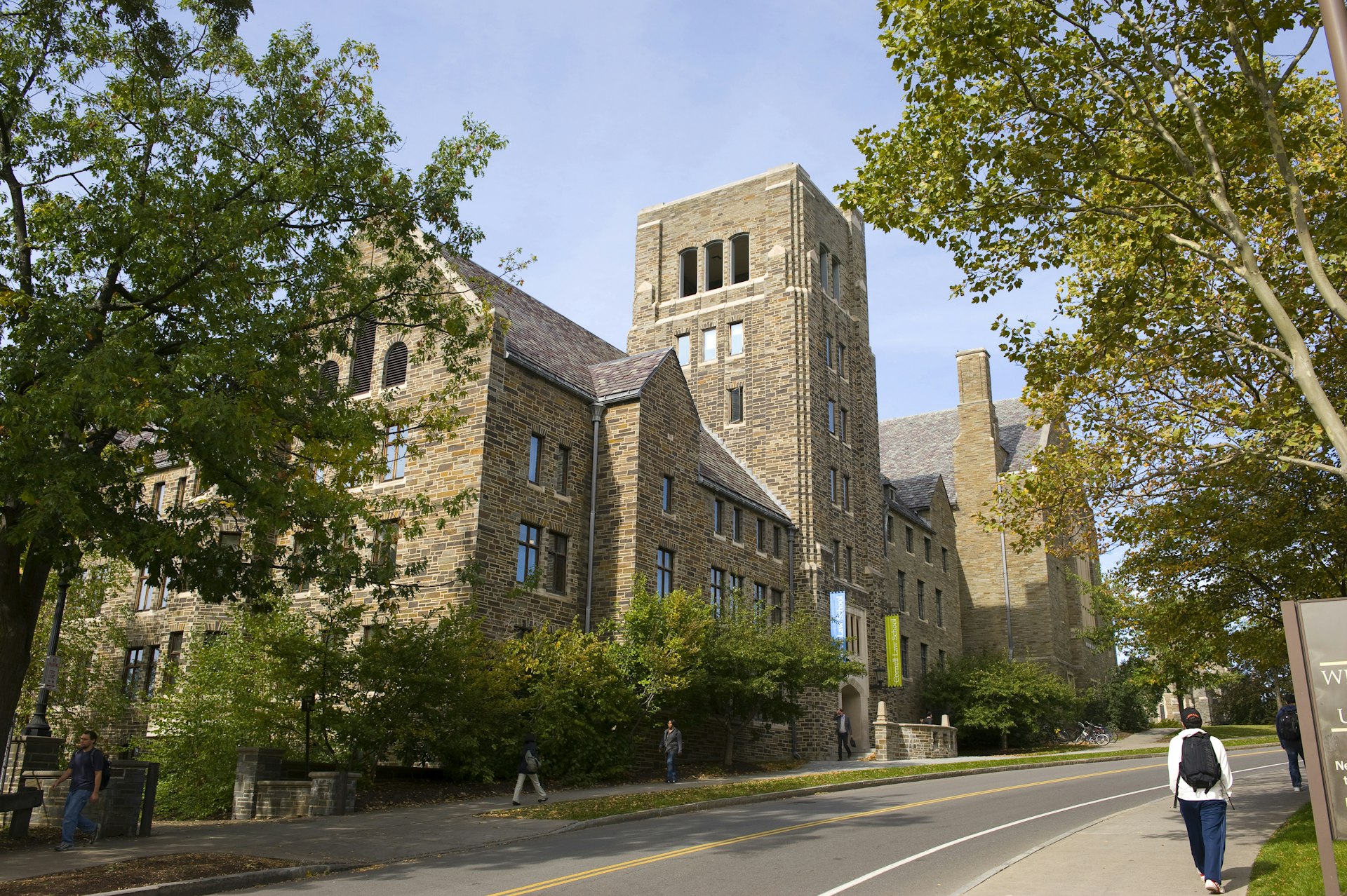 A student walks next to large buildings on the campus of Cornell University 