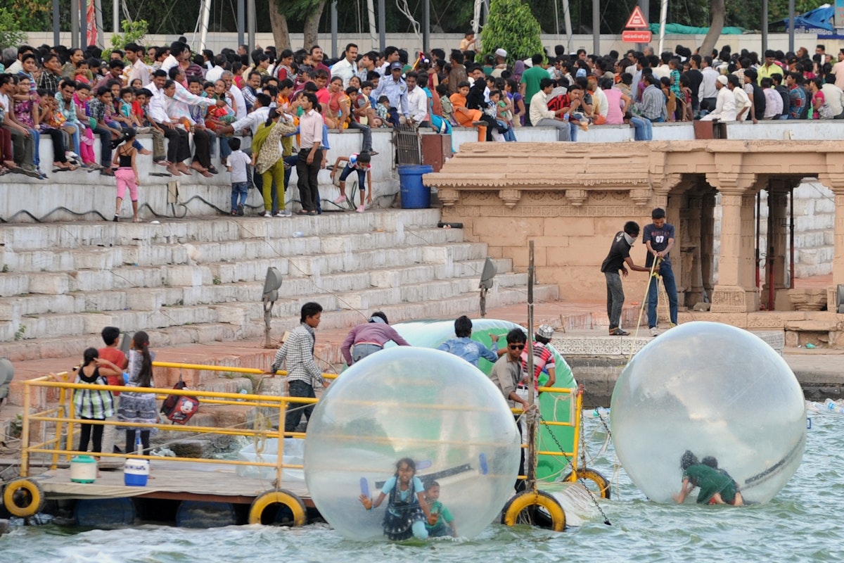 Youths enjoy a ride in floating spheres as tourists throng Kankaria Lake in Ahmedabad on June 3, 2012. Heatwave conditions persist over much of India as the country's expected moonsoon, crucial to farmers and growth in Asia's third-largest economy, has missed its normal arrival date but forecasters said they were confident the rains would arrive soon. Normally the rains begin sweeping across the subcontinent from June 1 to late September and in recent years they have started early.  AFP PHOTO / Sam PANTHAKY        (Photo credit should read SAM PANTHAKY/AFP/GettyImages)