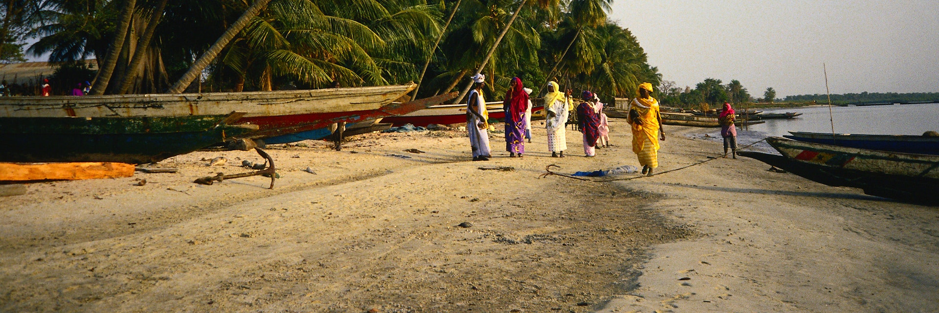 Women traders wait on the beach for a small boat to ferry them across to the island of Carabane - Casamance