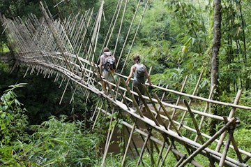 Backpackers crossing bamboo suspension bridge on trek from Kuching to Bidayuh village of Semban, near Kuching.