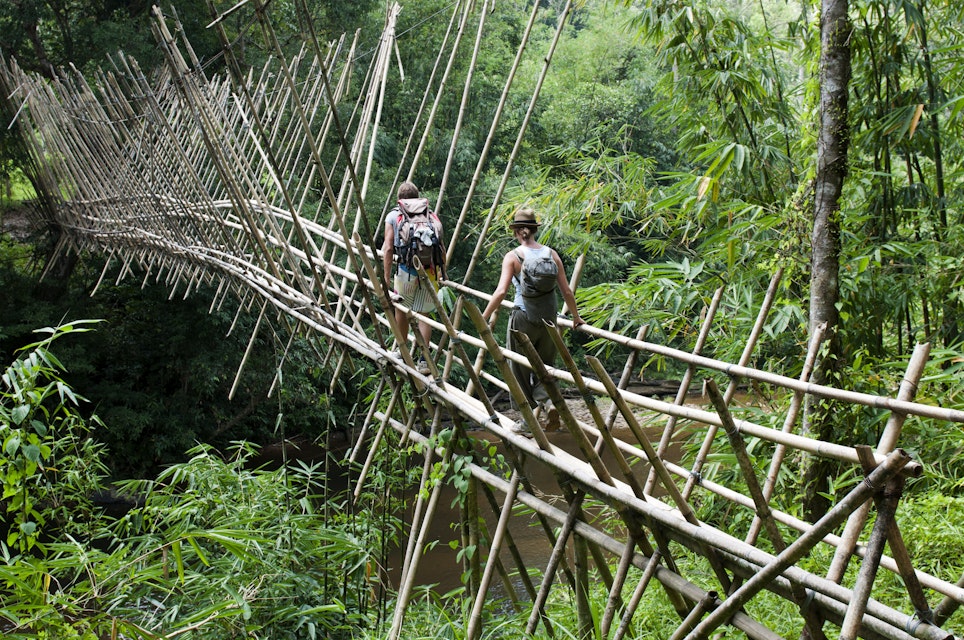Backpackers crossing bamboo suspension bridge on trek from Kuching to Bidayuh village of Semban, near Kuching.