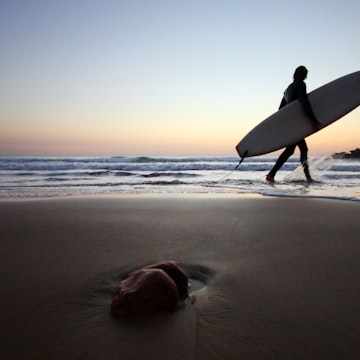 Surfer with surboard at sunset
