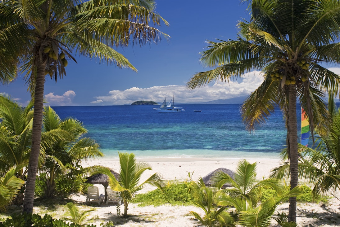 Sail boat seen through palm trees, Mamanuca Group islands, Fiji