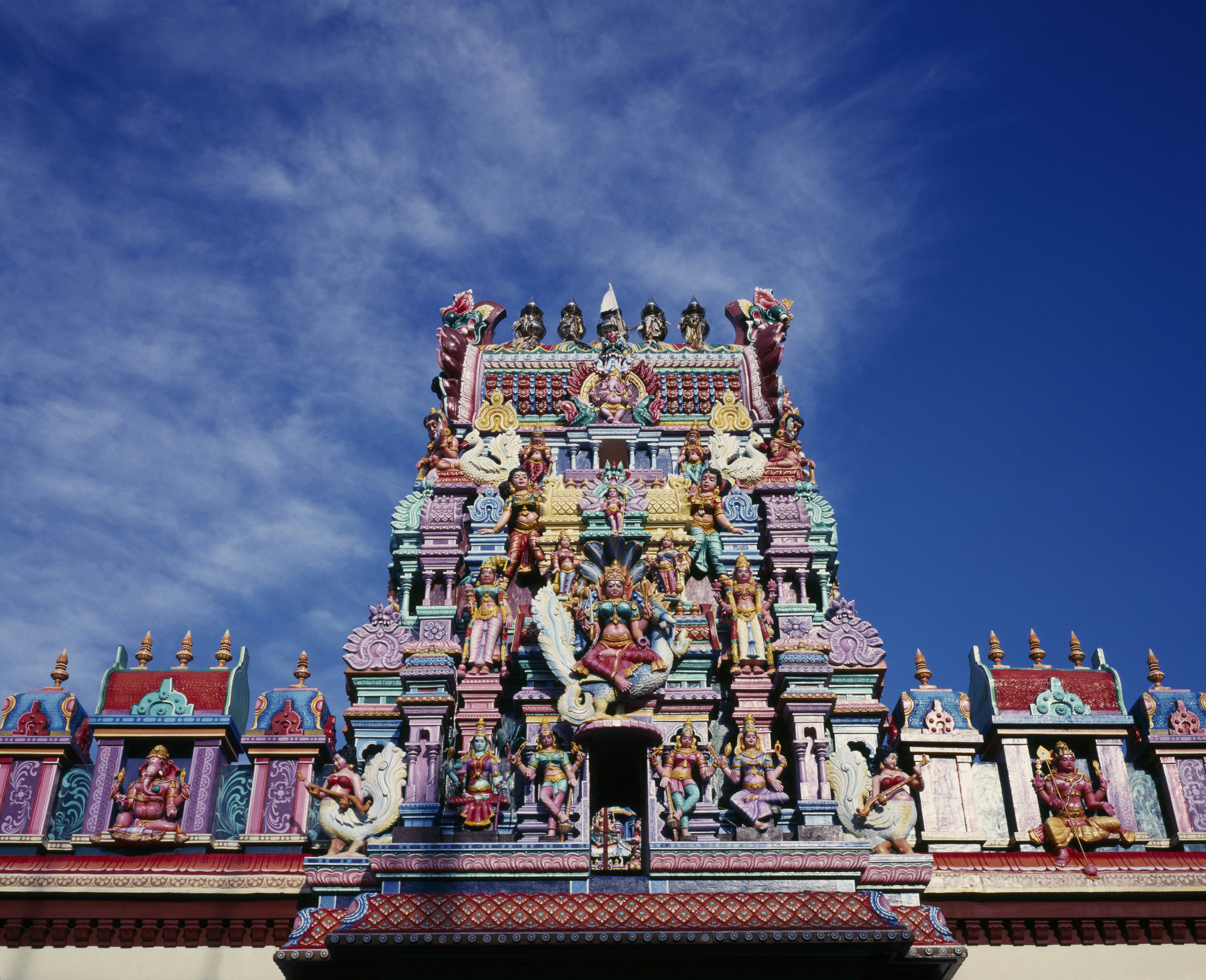 malaysia, penang, georgetown, sri mariamman temple. part view of exterior roof and gopuram painted tower decorated with brightly painted figures of hindu gods and characters.