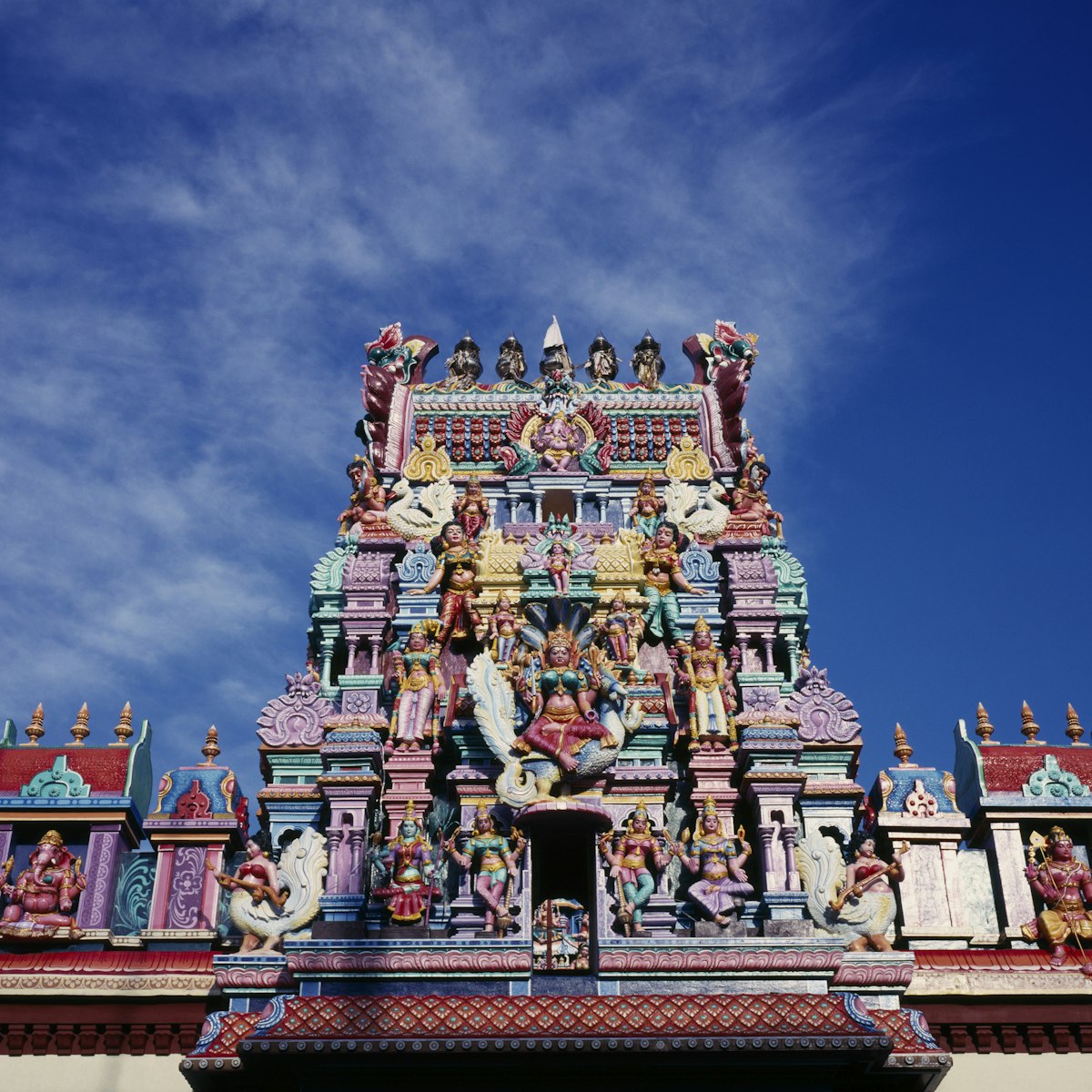 malaysia, penang, georgetown, sri mariamman temple. part view of exterior roof and gopuram painted tower decorated with brightly painted figures of hindu gods and characters.