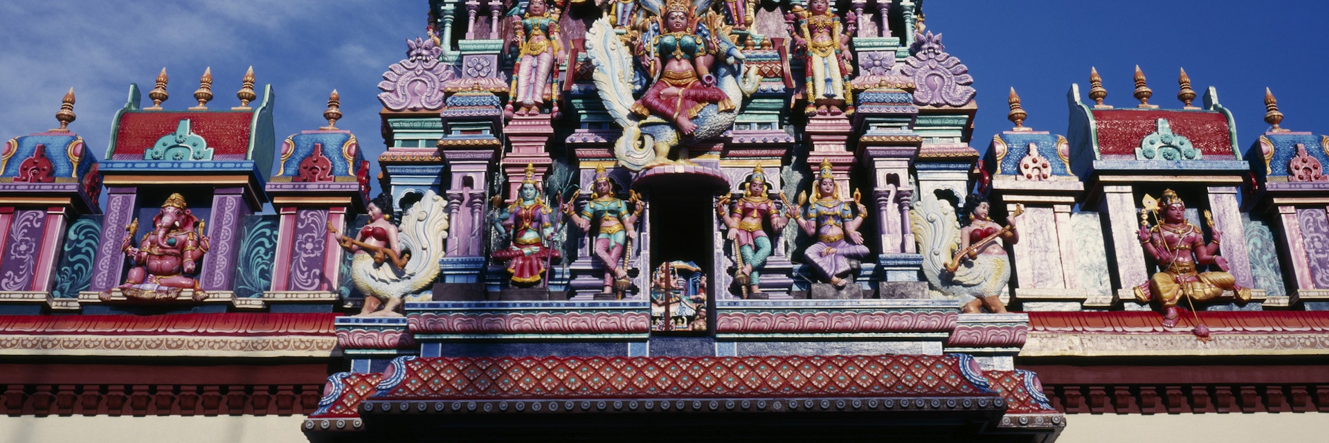 malaysia, penang, georgetown, sri mariamman temple. part view of exterior roof and gopuram painted tower decorated with brightly painted figures of hindu gods and characters.