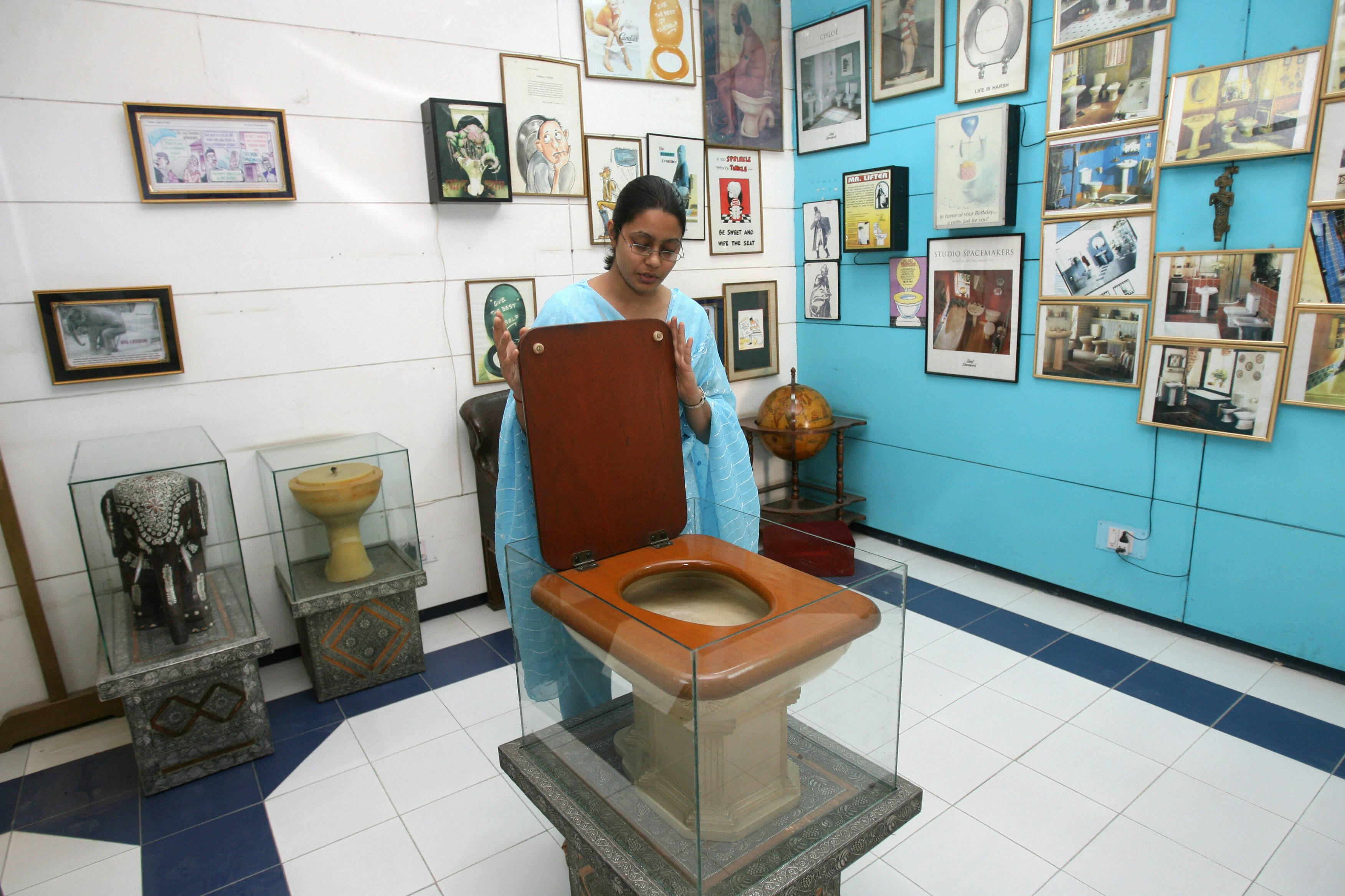 TO GO WITH STORY BY TRIPTI LAHIRI  An employee of the Sulabh International Museum of Toilets displays a Fancy Toilet used in the 1930s at the museum in New Delhi, 27 October 2007.   For India's low-cost toilet champion, each new loo means freedom not just from rampant disease, but one more chance to liberate someone from doing the awful job of disposing of someone else's waste. In the centuries-old caste system, with its ingrained fear of "pollution," the deepest revulsion has traditionally been reserved for those who do India's dirty work, such as taking away human waste from homes in buckets. AFP PHOTO/RAVEENDRAN (Photo credit should read RAVEENDRAN/AFP/Getty Images)