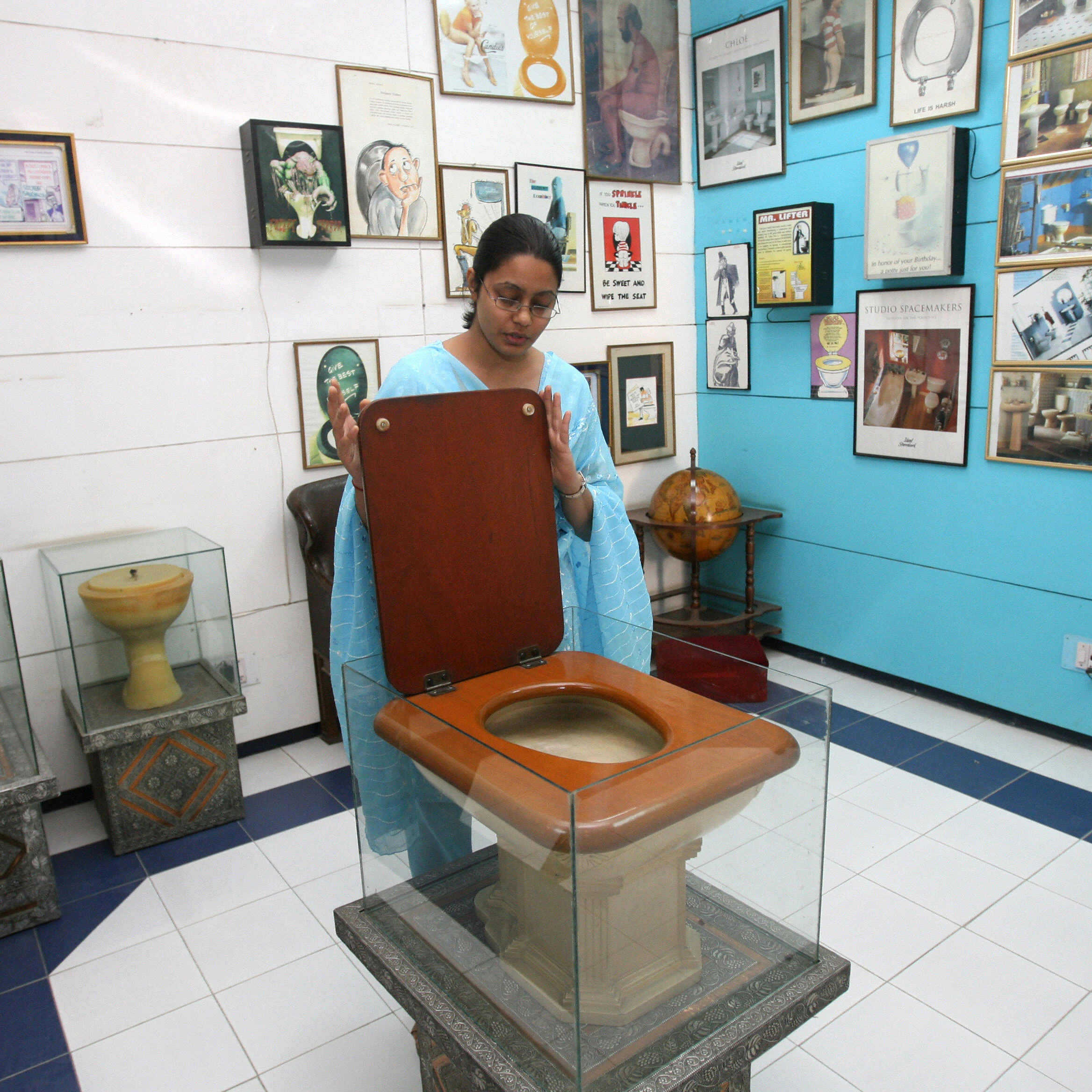 TO GO WITH STORY BY TRIPTI LAHIRI An employee of the Sulabh International Museum of Toilets displays a Fancy Toilet used in the 1930s at the museum in New Delhi, 27 October 2007. For India's low-cost toilet champion, each new loo means freedom not just from rampant disease, but one more chance to liberate someone from doing the awful job of disposing of someone else's waste. In the centuries-old caste system, with its ingrained fear of "pollution," the deepest revulsion has traditionally been reserved for those who do India's dirty work, such as taking away human waste from homes in buckets. AFP PHOTO/RAVEENDRAN (Photo credit should read RAVEENDRAN/AFP/Getty Images)