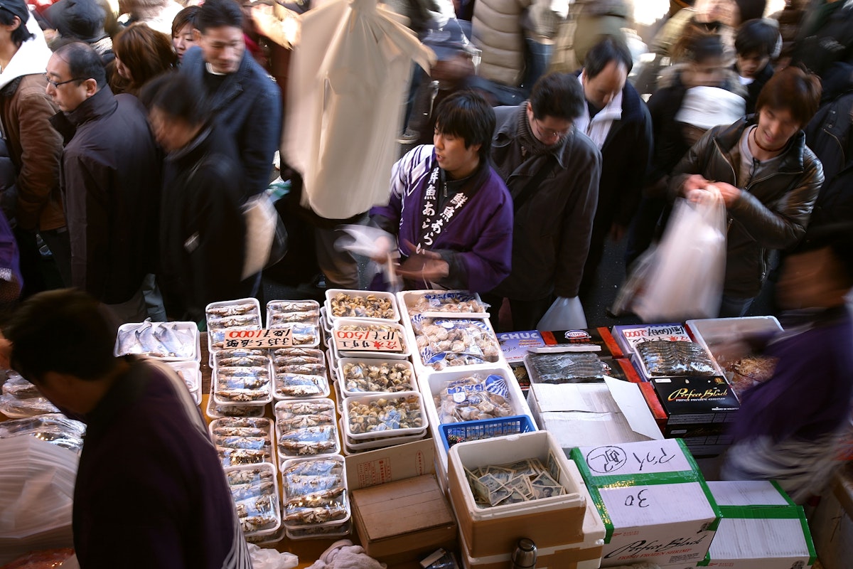 TOKYO - DECEMBER 31:  A fishmonger sells seafood at a fish stall in the Ameya Yokocho street market on December 31, 2008 in Tokyo, Japan. People shop around in preparation to celebrate the New Year holidays at the market featuring over 500 stalls, which sell various products such as fresh fish, dried food, vegetables, fruits, spices, clothes, bags and cosmetics on the narrow street.  (Photo by Kiyoshi Ota/Getty Images)