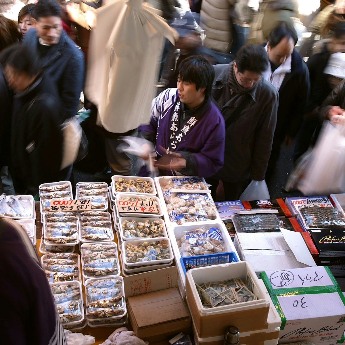 TOKYO - DECEMBER 31:  A fishmonger sells seafood at a fish stall in the Ameya Yokocho street market on December 31, 2008 in Tokyo, Japan. People shop around in preparation to celebrate the New Year holidays at the market featuring over 500 stalls, which sell various products such as fresh fish, dried food, vegetables, fruits, spices, clothes, bags and cosmetics on the narrow street.  (Photo by Kiyoshi Ota/Getty Images)