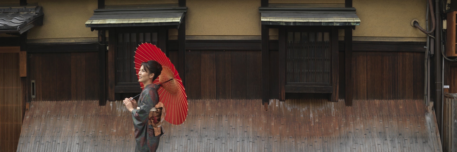 Japan, Kyoto, Gion, woman in kimono with red oilpaper umbrella, walking in street