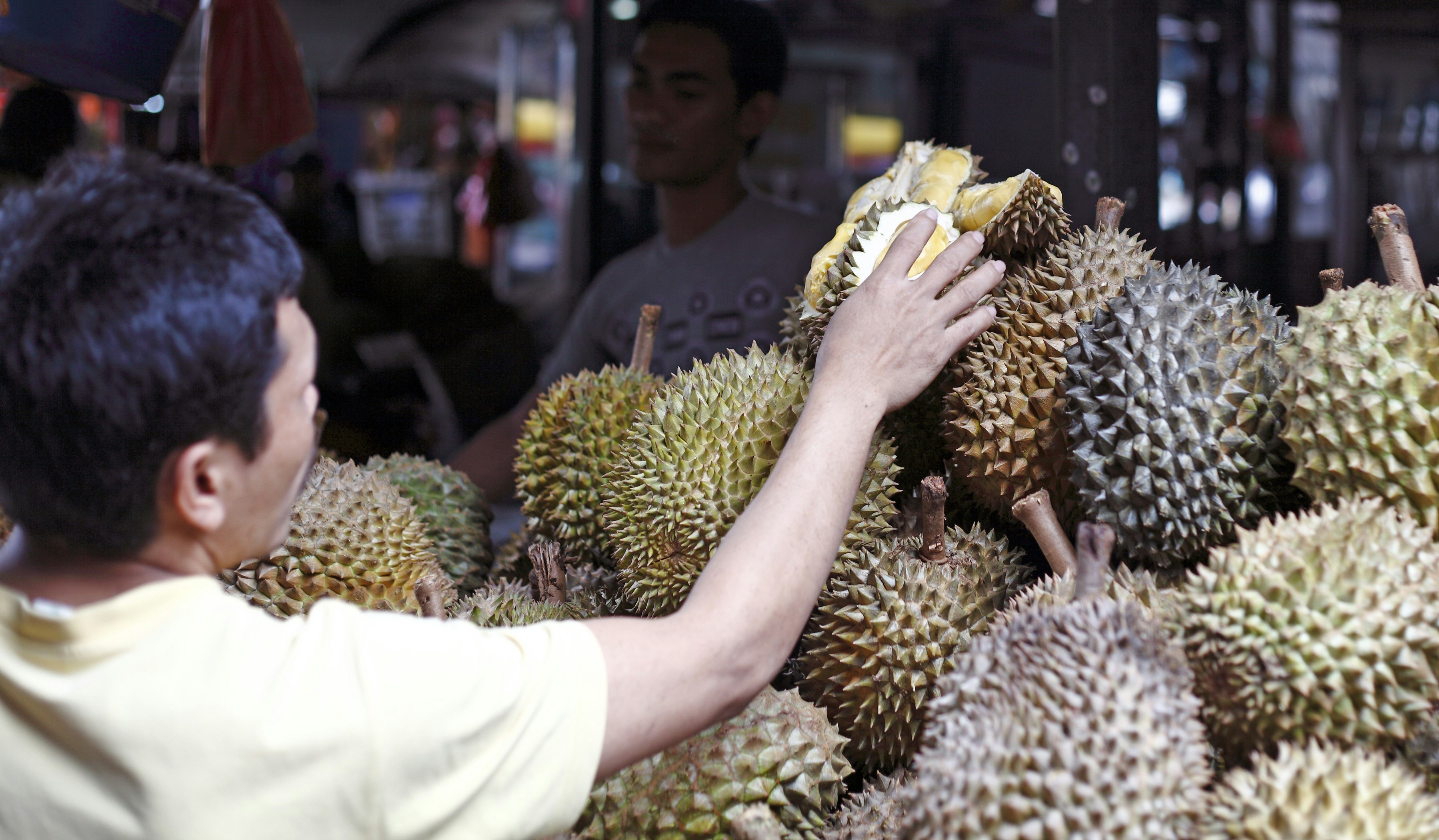 KUALA LUMPUR, MALAYSIA - SEPT 11: A shopper at a durian fruit stall on September 11, 2011 in Bazaar Baru Chow Kit, Kuala Lumpur, Malaysia. Durian is revered in Southeast Asia as the King of Fruits.; Shutterstock ID 84916264; Your name (First / Last): Lauren Gillmore; GL account no.: 56530; Netsuite department name: Online-Design; Full Product or Project name including edition: 65050/ Online Design /LaurenGillmore/POI