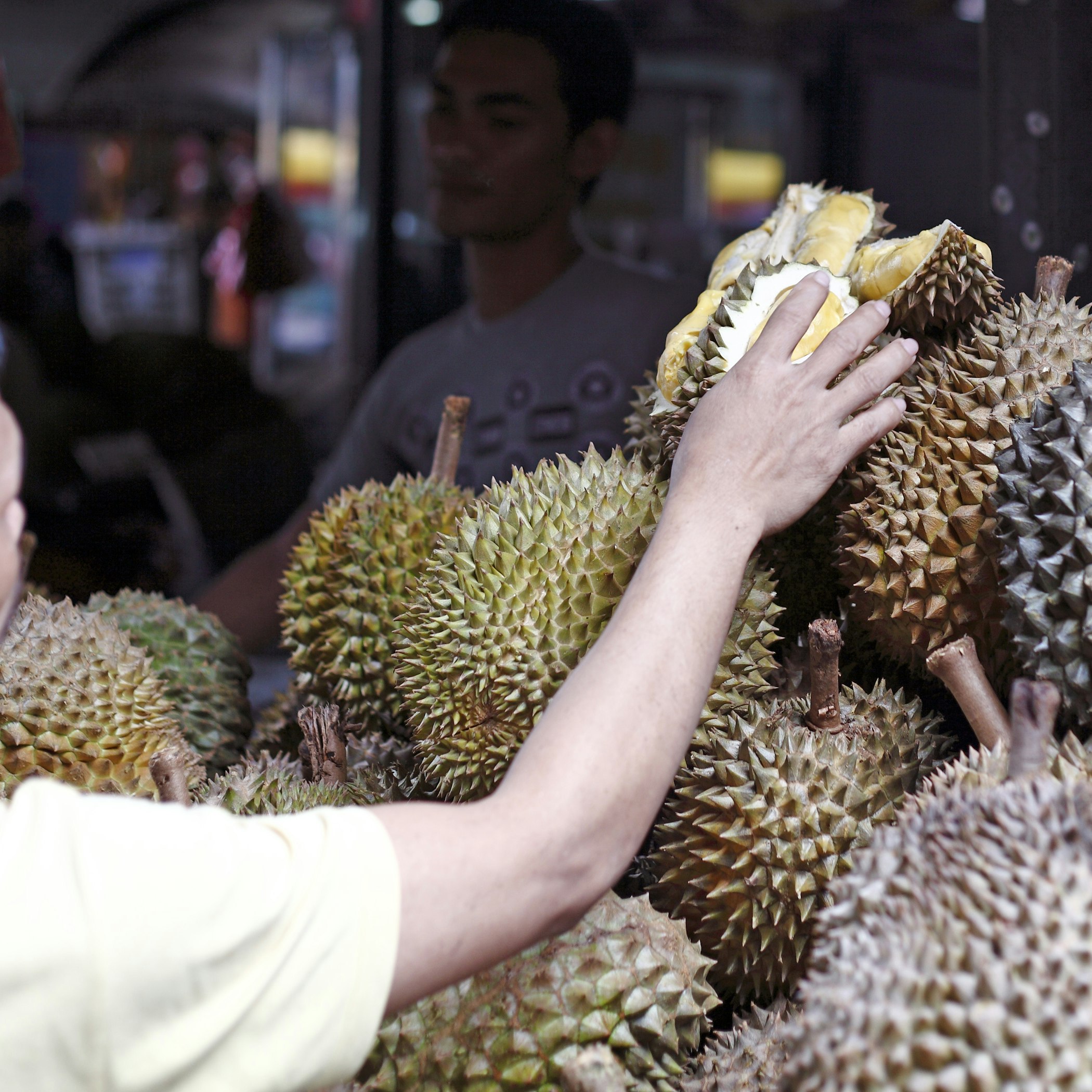 KUALA LUMPUR, MALAYSIA - SEPT 11: A shopper at a durian fruit stall on September 11, 2011 in Bazaar Baru Chow Kit, Kuala Lumpur, Malaysia. Durian is revered in Southeast Asia as the King of Fruits.; Shutterstock ID 84916264; Your name (First / Last): Lauren Gillmore; GL account no.: 56530; Netsuite department name: Online-Design; Full Product or Project name including edition: 65050/ Online Design /LaurenGillmore/POI