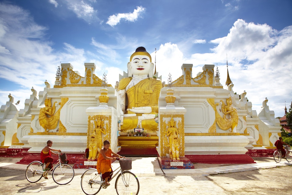 新手僧侣在Yan Aung Hsu Hsu taung Pyi Pagoda附近的Yan Aung aung hsu taung taung taung骑自行车经过26英尺高的坐着佛像。