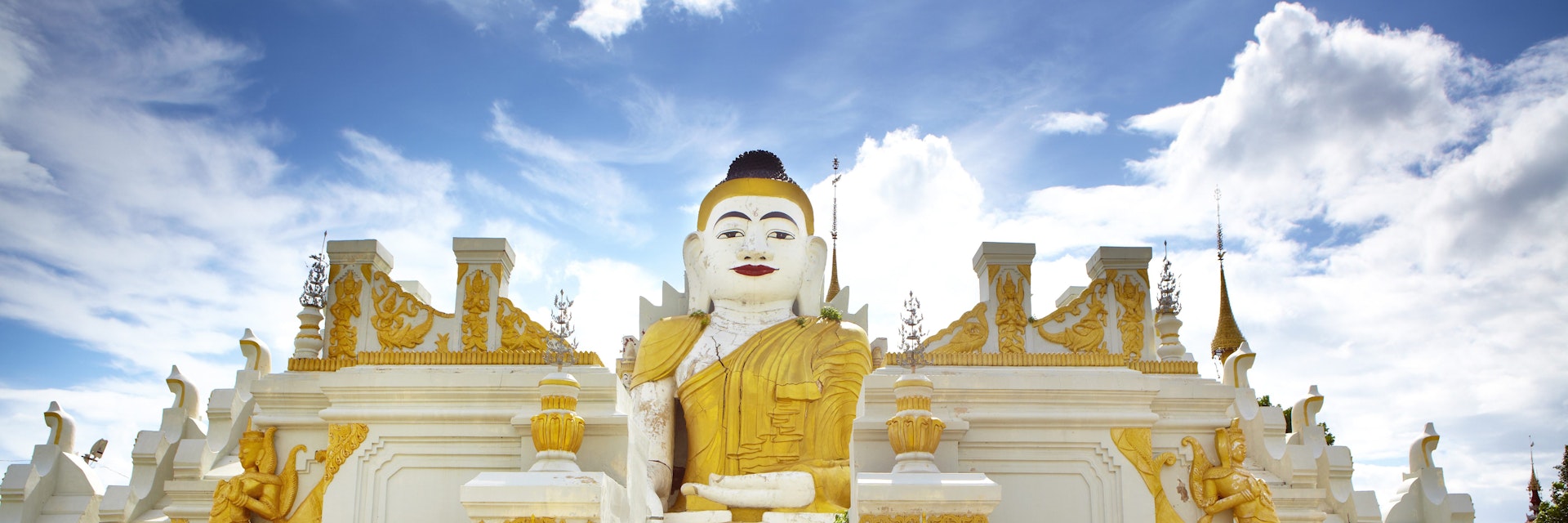 Novice monks cycling past 26-foot high sitting Buddha at Yan Aung Nan Aung Hsu Taung Pyi Pagoda near Inle Lake.