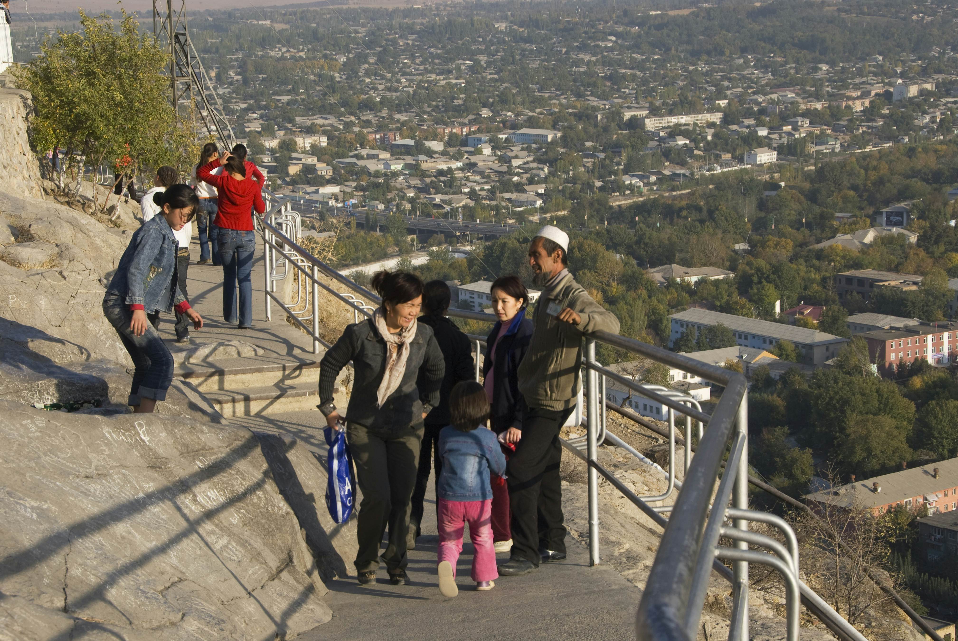 Kyrgyz people enjoying themselves on Solomon's Throne with city overview.